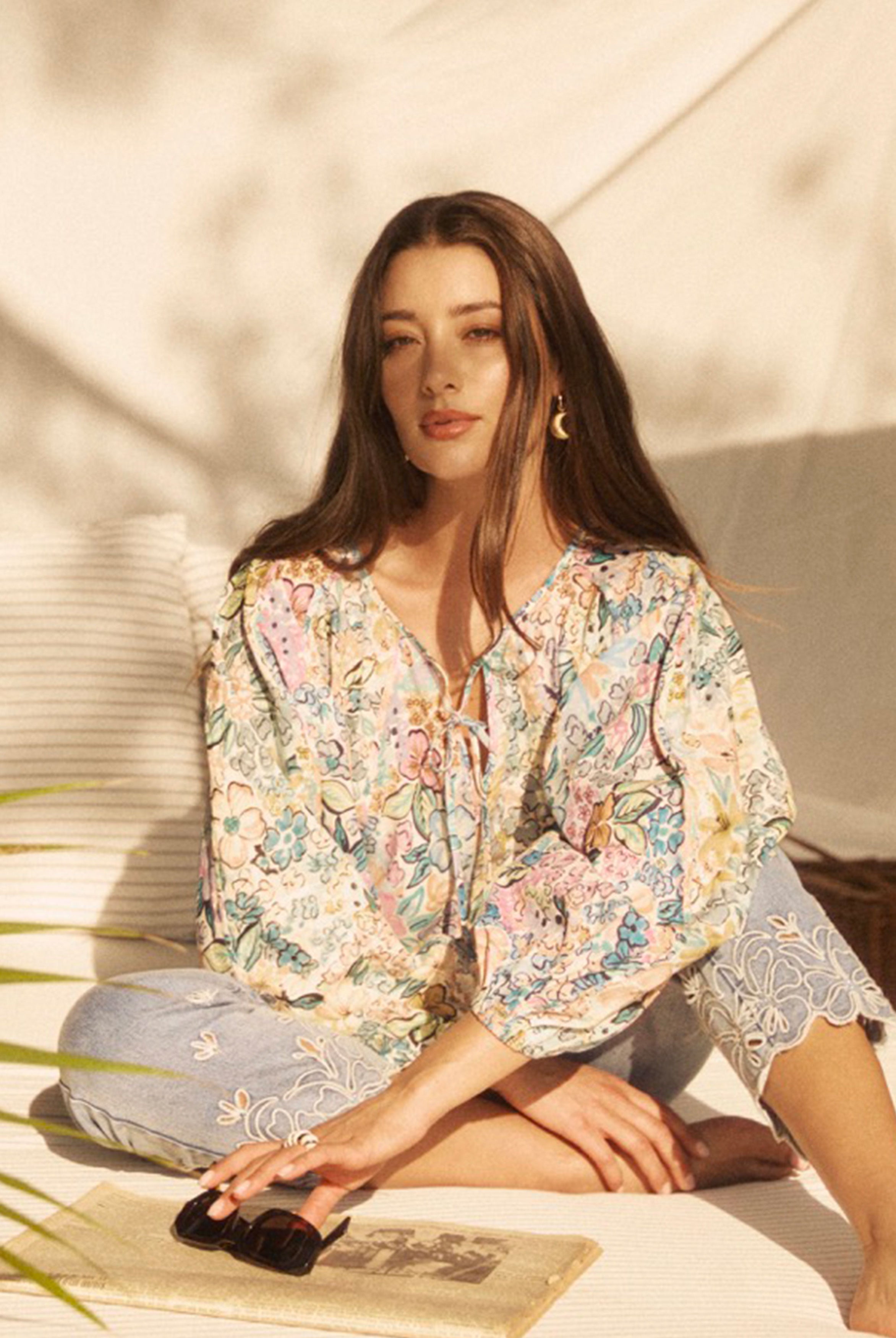 Model seated wearing Ambush Floral blouse, showcasing vibrant print and relaxed fit by French Dressing Jeans (FDJ)